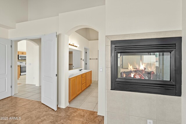 bathroom featuring a high ceiling, vanity, a multi sided fireplace, and tile patterned floors