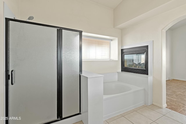 bathroom with a shower stall, a bath, and tile patterned floors