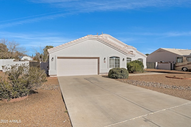 ranch-style house featuring a tiled roof, fence, concrete driveway, and stucco siding