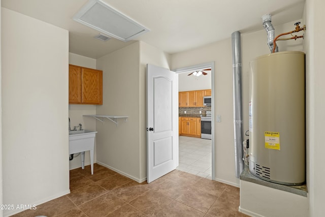 laundry area featuring cabinet space, attic access, light tile patterned floors, visible vents, and gas water heater