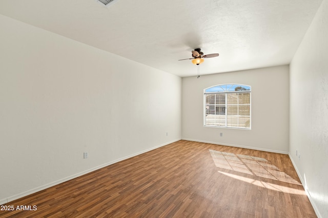 spare room featuring a ceiling fan, baseboards, and wood finished floors