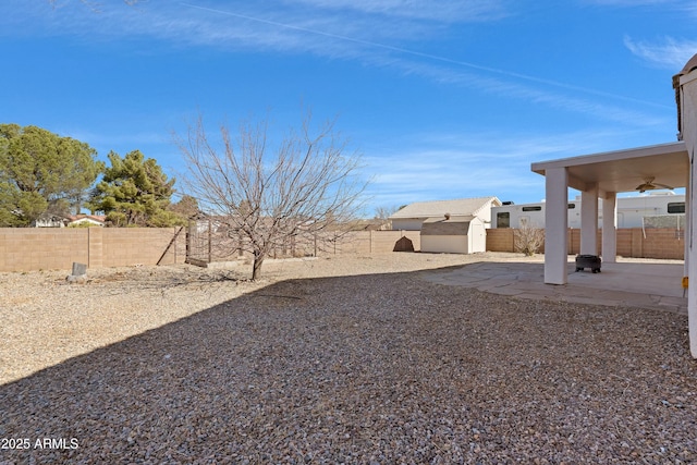 view of yard with a storage shed, a patio area, an outbuilding, and a fenced backyard