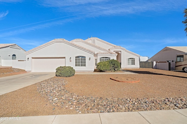 ranch-style house featuring driveway, a garage, a tile roof, fence, and stucco siding