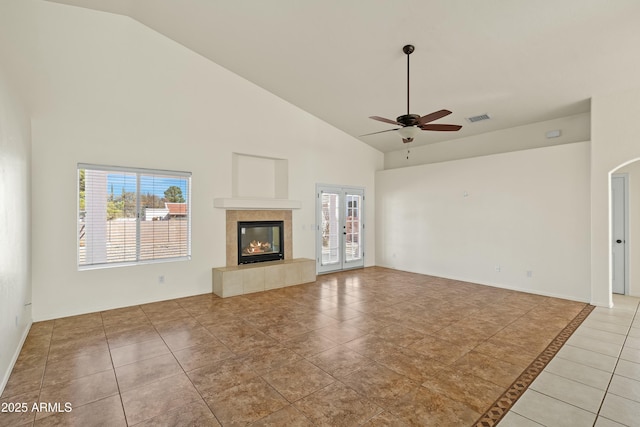 unfurnished living room featuring french doors, visible vents, light tile patterned flooring, ceiling fan, and a tile fireplace