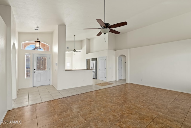 foyer with light tile patterned floors, arched walkways, baseboards, ceiling fan, and high vaulted ceiling