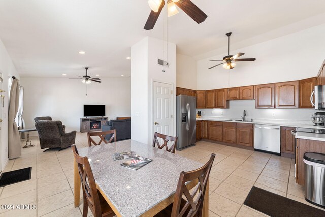 dining area with light tile patterned floors, high vaulted ceiling, sink, and ceiling fan