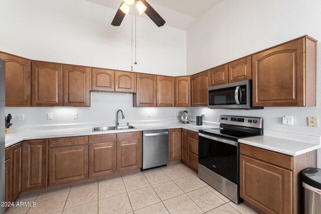 kitchen with light tile patterned floors, appliances with stainless steel finishes, sink, high vaulted ceiling, and ceiling fan