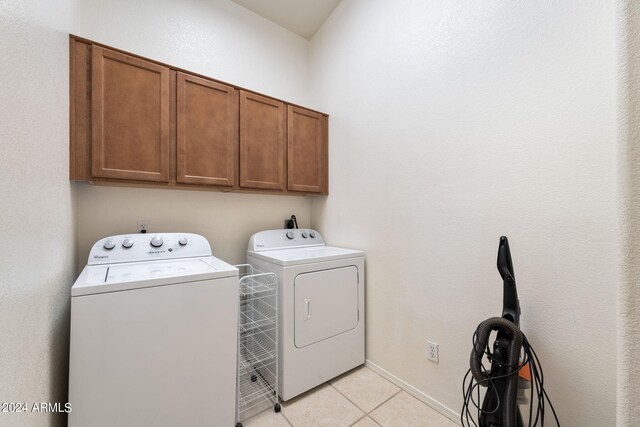 laundry area with washing machine and clothes dryer, cabinets, and light tile patterned floors