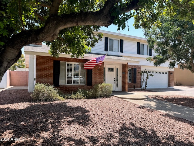 traditional-style house with a garage, concrete driveway, and brick siding