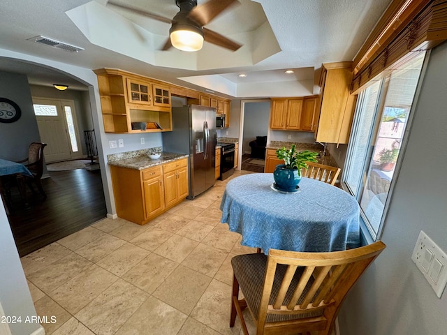 kitchen featuring a tray ceiling, light wood-type flooring, a wealth of natural light, and ceiling fan