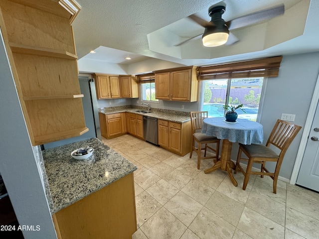 kitchen featuring light stone countertops, baseboards, a tray ceiling, and dishwasher