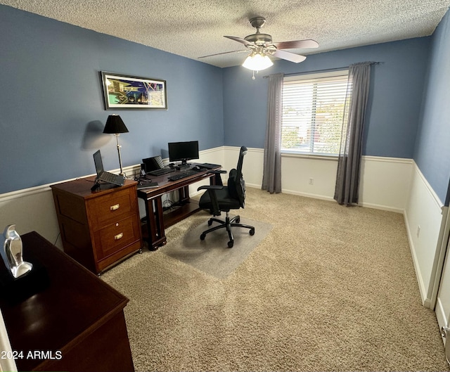 home office featuring a textured ceiling, baseboards, a ceiling fan, and light colored carpet