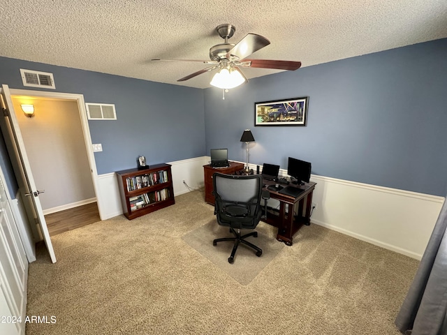 carpeted office space featuring a textured ceiling, ceiling fan, and visible vents