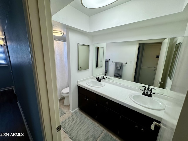 full bathroom featuring double vanity, a sink, and toilet