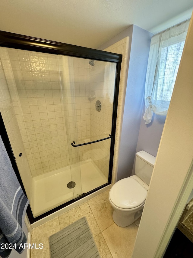 full bath with toilet, a shower stall, and tile patterned flooring