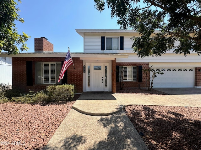 view of front of home featuring driveway, a garage, a chimney, and brick siding