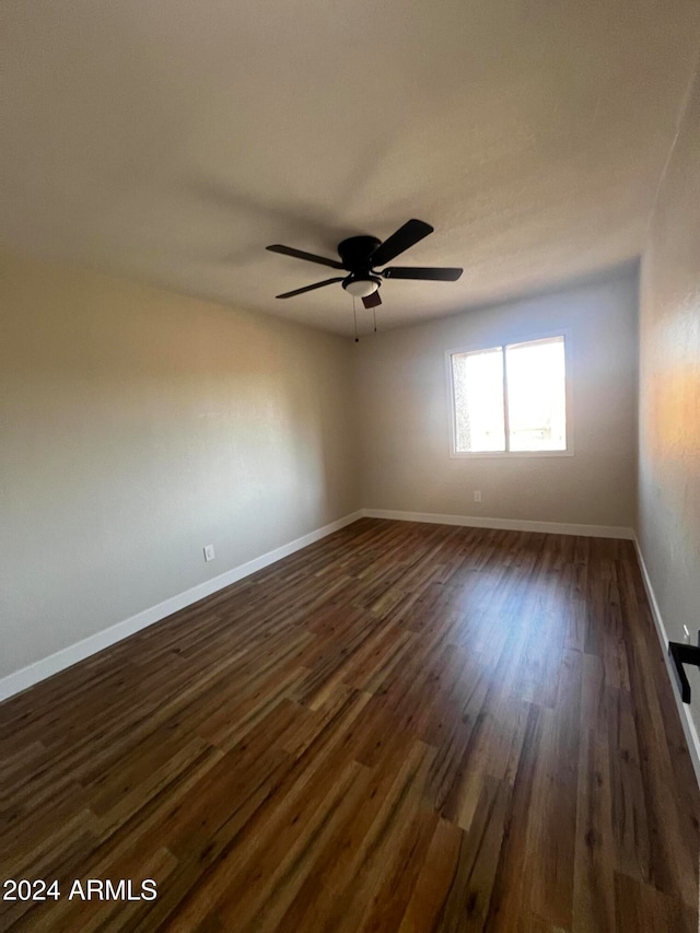 empty room with dark hardwood / wood-style flooring and ceiling fan