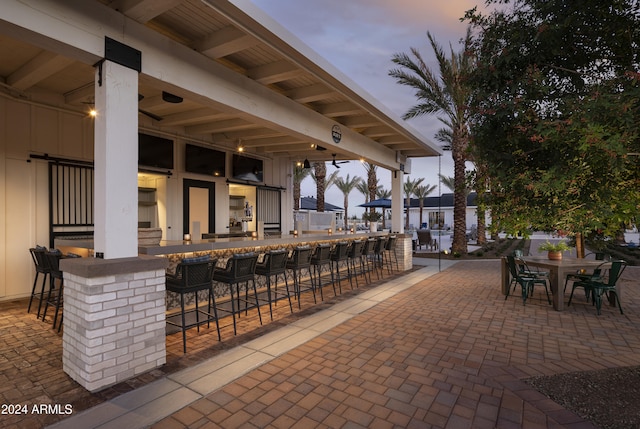 patio terrace at dusk featuring a bar