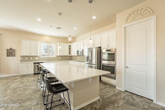 kitchen featuring white cabinetry, a breakfast bar area, a center island, and appliances with stainless steel finishes