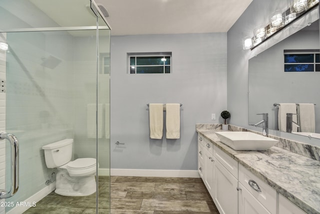 bathroom with toilet, hardwood / wood-style flooring, vanity, and a shower with door