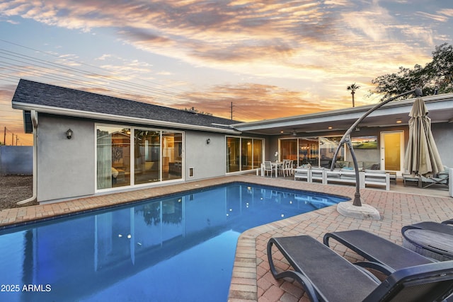 pool at dusk with a patio area