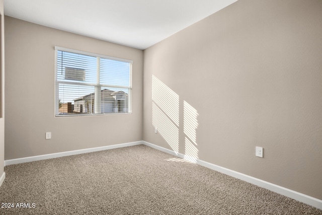 spare room featuring carpet flooring and baseboards