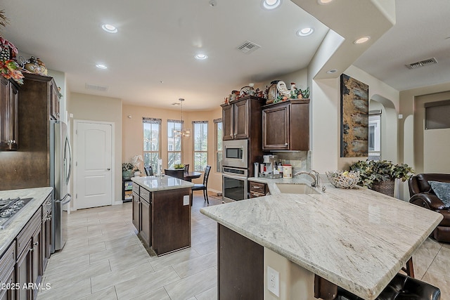 12738 W Brookhart Way, Peoria, AZ 85383 - kitchen featuring stainless steel appliances, a sink, a kitchen island, dark brown cabinetry, and a peninsula