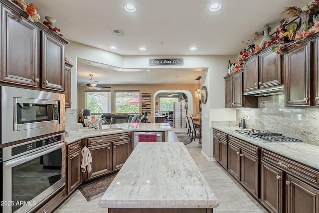12738 W Brookhart Way, Peoria, AZ 85383 - kitchen featuring appliances with stainless steel finishes, arched walkways, recessed lighting, a peninsula, and decorative backsplash