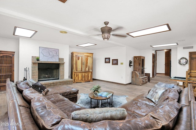 1338 W Mountain View Dr, Mesa, AZ 85201 - living area featuring a ceiling fan, light wood-style flooring, a brick fireplace, baseboards, and a skylight