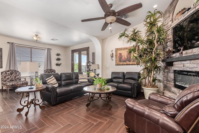 living room featuring ceiling fan, a fireplace, and dark parquet floors