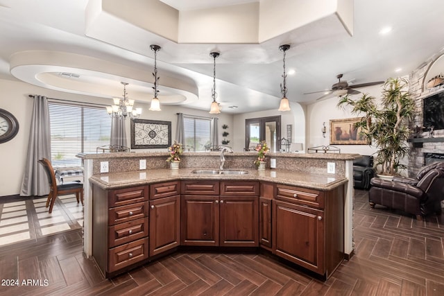 kitchen with hanging light fixtures, sink, a kitchen island with sink, and dark parquet floors