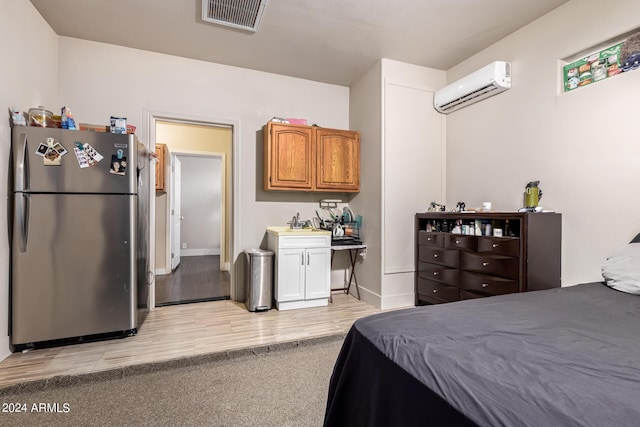 bedroom featuring stainless steel fridge, a wall unit AC, and light hardwood / wood-style flooring