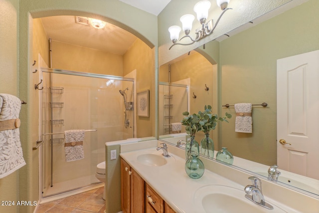 bathroom with tile patterned floors, vanity, a notable chandelier, toilet, and a shower with shower door