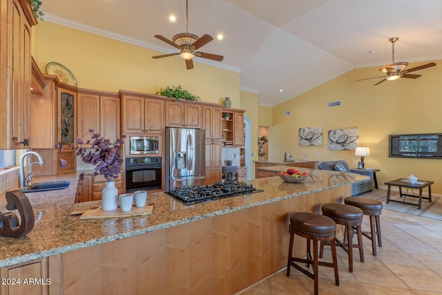 kitchen featuring a kitchen bar, kitchen peninsula, light stone countertops, and stainless steel appliances