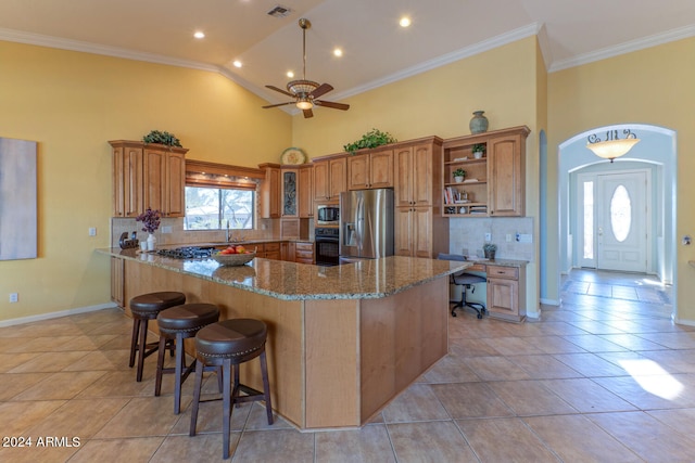 kitchen with ceiling fan, tasteful backsplash, stone countertops, a kitchen bar, and appliances with stainless steel finishes