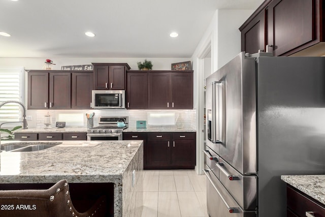 kitchen featuring light stone countertops, sink, backsplash, appliances with stainless steel finishes, and light tile patterned flooring