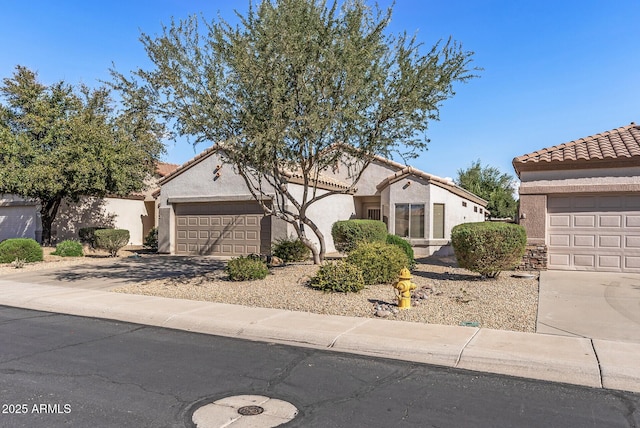 view of front of house with an attached garage, concrete driveway, stucco siding, and a tiled roof