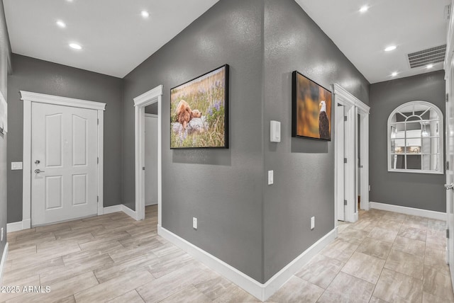 hallway featuring visible vents, recessed lighting, a textured wall, and baseboards