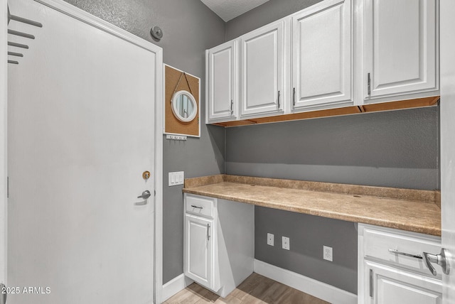 laundry area featuring light wood finished floors and baseboards
