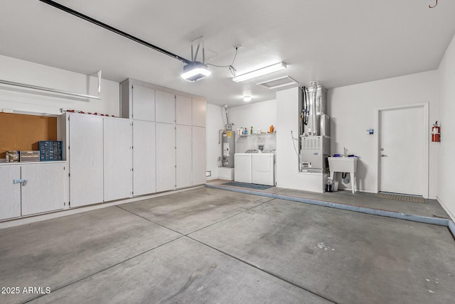 garage featuring heating unit, water heater, a garage door opener, a sink, and washing machine and dryer