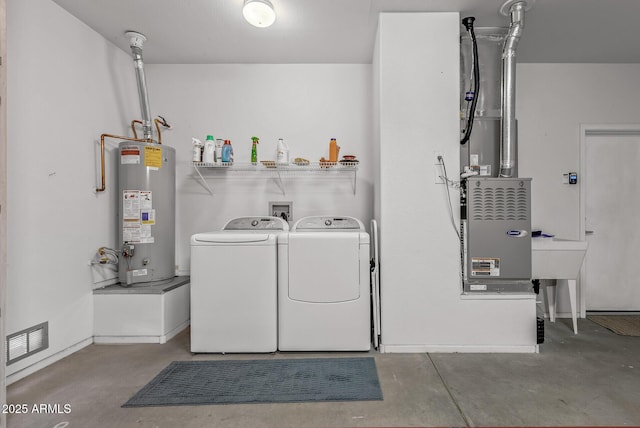 washroom with gas water heater, visible vents, washing machine and clothes dryer, and laundry area