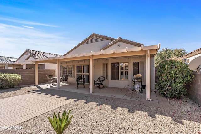 rear view of property featuring a patio, a pergola, stucco siding, and fence
