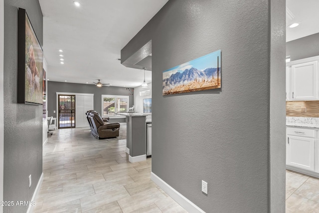 hallway with a textured wall, recessed lighting, and baseboards