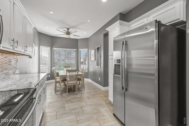 kitchen featuring white cabinets, ceiling fan, light stone countertops, and appliances with stainless steel finishes