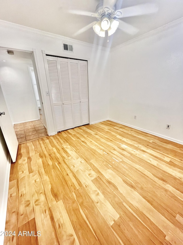 unfurnished bedroom featuring ornamental molding, a closet, ceiling fan, and light hardwood / wood-style flooring