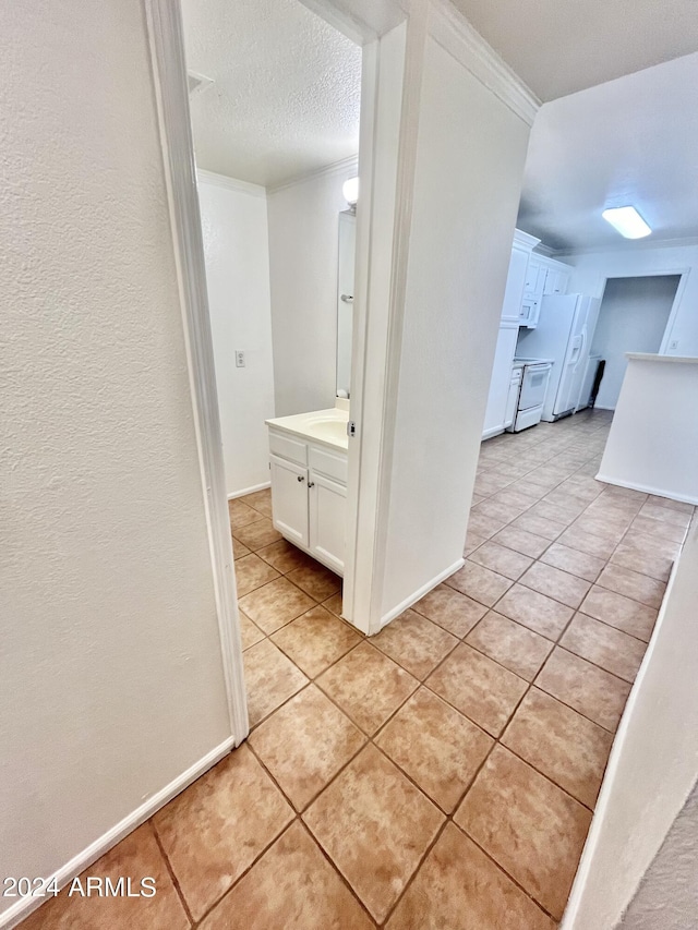 corridor featuring crown molding, light tile patterned flooring, and a textured ceiling