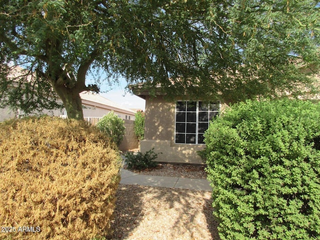 view of side of home with fence and stucco siding