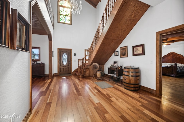 entrance foyer with an inviting chandelier, a towering ceiling, and wood-type flooring