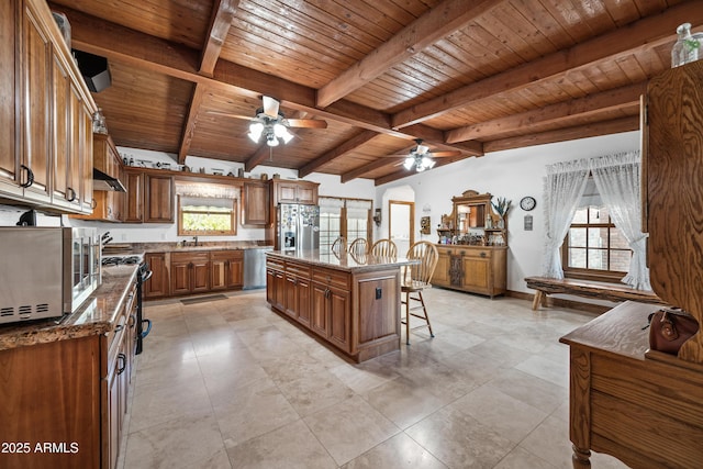 kitchen with a breakfast bar, plenty of natural light, stainless steel appliances, and a center island