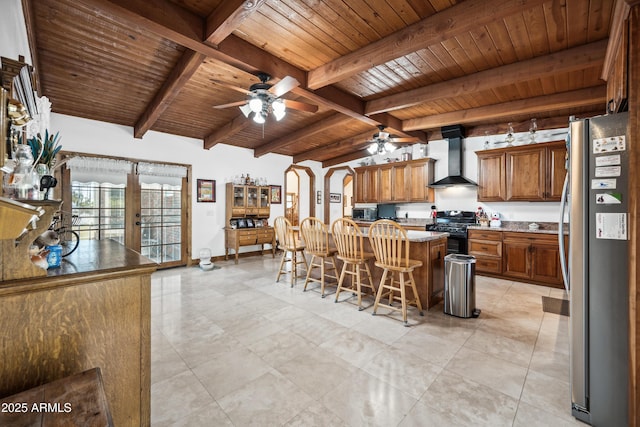 kitchen featuring a breakfast bar area, appliances with stainless steel finishes, french doors, wall chimney range hood, and a kitchen island